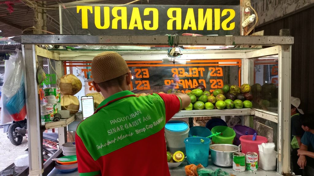 Ajang Rohimat menjajakan Es Sinar Garut miliknya di bilangan Jagakarsa, Jakarta Selatan. Ia mengenakan pakaian resmi yang menjadi ciri khas Paguyuban Sinar Garut Asli (PSGA).