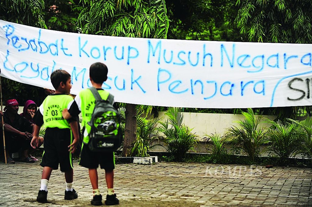 Anak-anak melihat spanduk yang dibentangkan oleh aktivis dari Masyarakat Peduli Berantas Korupsi di halaman Pengadilan Negeri Kota Semarang, Jawa Tengah, Rabu (9/11). Para aktivis tersebut meminta ketegasan jaksa dan hakim dalam menghukum para koruptor yang banyak melibatkan pejabat daerah, seperti bupati dan wali kota.