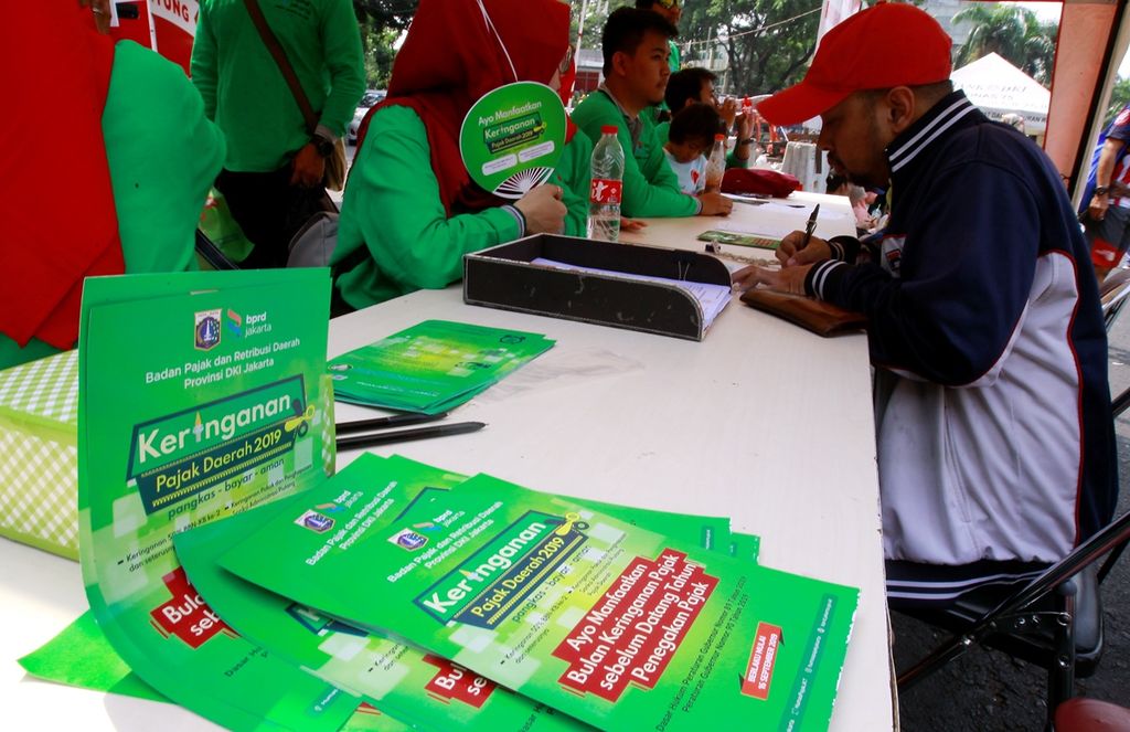 Petugas membantu warga dalam mengisi formulir pajak di kawasan hari bebas kendaraan bermotor, Bundaran Hotel Indonesia, Jakarta, Minggu (22/9/2019). 