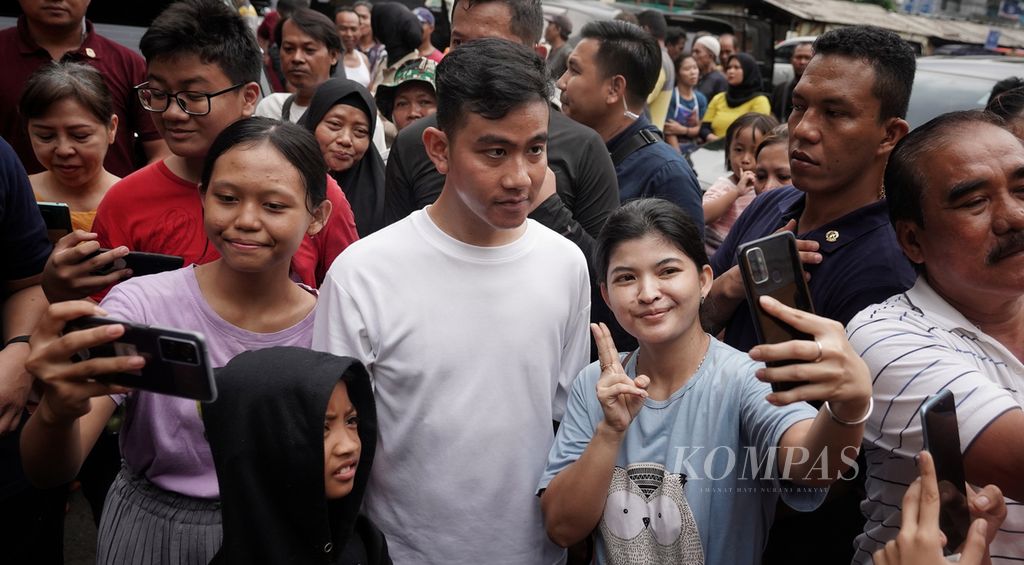 Calon wakil presiden Gibran Rakabuming Raka melayani warga berswafoto ketika dirinya mengisi hari berkampanyenya dengan mengunjungi Pasar Rawasari, Cempaka Putih, Jakarta, Minggu (3/12/2023).