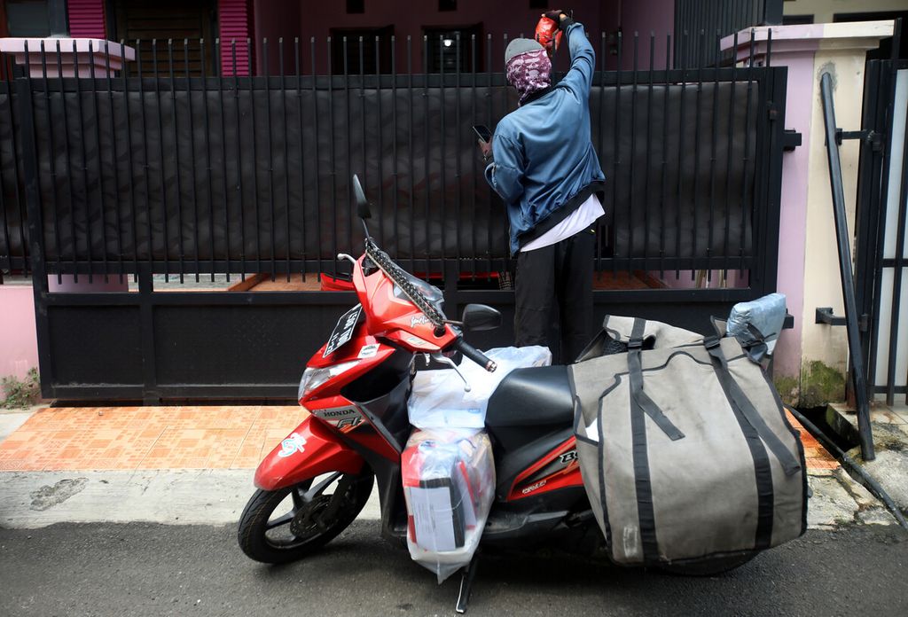Kurir menyerahkan barang kepada pelanggan di kawasan Duren Sawit, Jakarta, Selasa (5/4/2022).