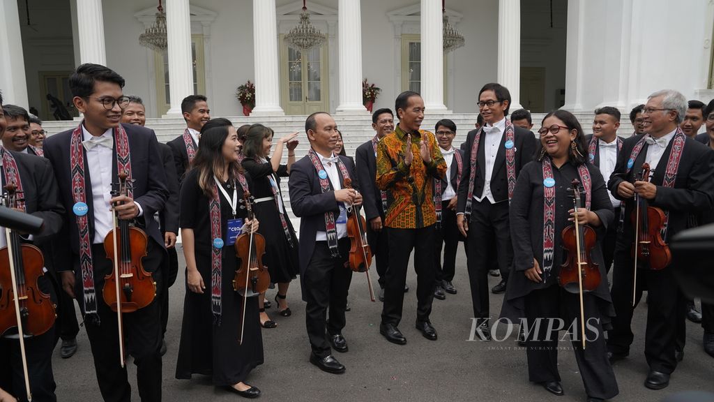 Presiden Joko Widodo berbincang dengan komponis Addie MS yang memimpin Twilite Orchestra setelah berfoto bersama di tangga istana dalam rangkaian Kompas100 CEO Forum powered by East Ventures di Istana Merdeka, Jakarta, Jumat (2/12/2022).  