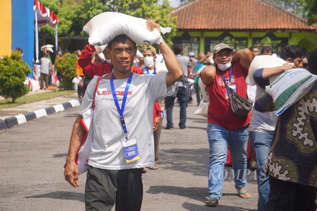 Presiden Joko Widodo mengecek penyaluran bantuan pangan di Gudang Bulog, Klahang, Sokaraja, Banyumas, Jawa Tengah, Rabu (3/1/2024). Tampak warga penerima bantuan beras dan sembako menggotong bantuan dari negara.