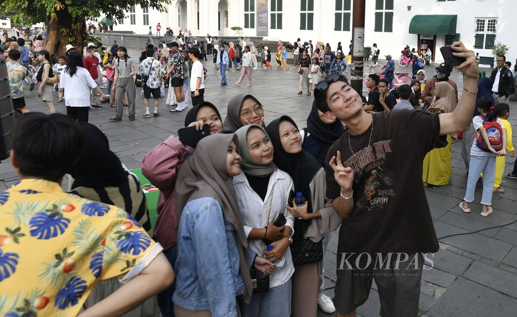 Pengunjung berswafoto bersama salah seorang mahasiswa dari Universitas Keimyung, Daegu, Korea Selatan, di Taman Fatahillah Kota Tua, Jakarta Barat, Rabu (5/7/2023). 