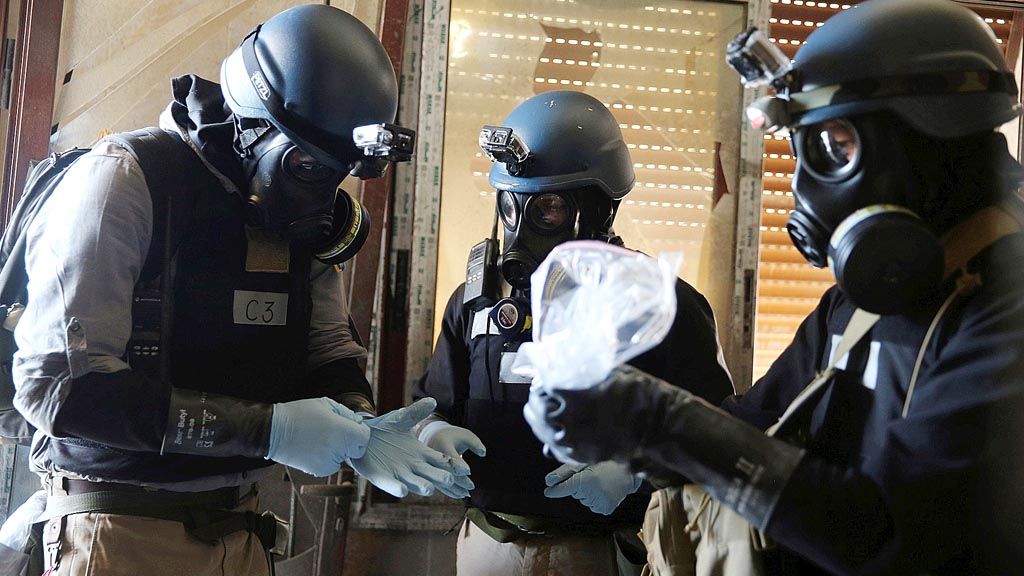 Tim ahli  senjata kimia Perserikatan Bangsa-Bangsa dengan mengenakan  masker gas memegang kantong plastik berisi sampel dari salah satu lokasi serangan senjata kimia yang diduga terjadi di lingkungan Ain Tarma di Damaskus, Suriah, pada Kamis, 29 Agustus 2013.  