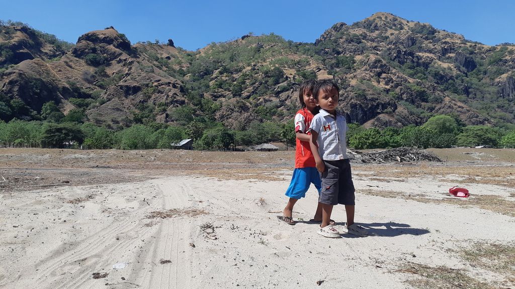 Dua bocah berjalan di kaki bukit di Wini, Kecamatan Insana Utara, Kabupaten Timor Tengah Utara, NTT, Minggu (12/6/2022). Daerah itu dipagari bukit batu.
