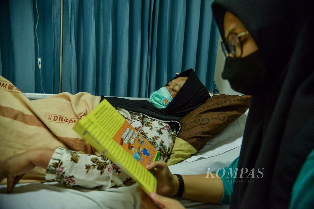 Seorang remaja membaca selebaran berisi penanganan demam berdarah dengue (DBD) di samping pasien DBD di Rumah Sakit Umum Daerah Cibinong, Kabupaten Bogor, Jawa Barat, awal Juni 2023.