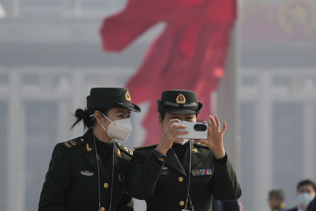 Dua perempuan anggota militer China mengambil foto di Lapangan Tiananmen di luar gedung Balai Agung Rakyat menjelang sidang pembuka parlemen tahunan Kongres Rakyat Nasional atau National People’s Congress (NPC) ke-14 di Beijing, China, Sabtu (4/3/2023).  