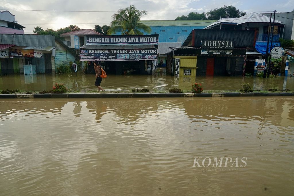 Warga menerobos banjir yang menggenangi kawasan Pasar Panjang Kendari, Sulawesi Selatan, untuk berangkat kerja, Senin (4/3/2024). Sejumlah kawasan di kota ini sempat terendam banjir setelah hujan beberapa waktu.
