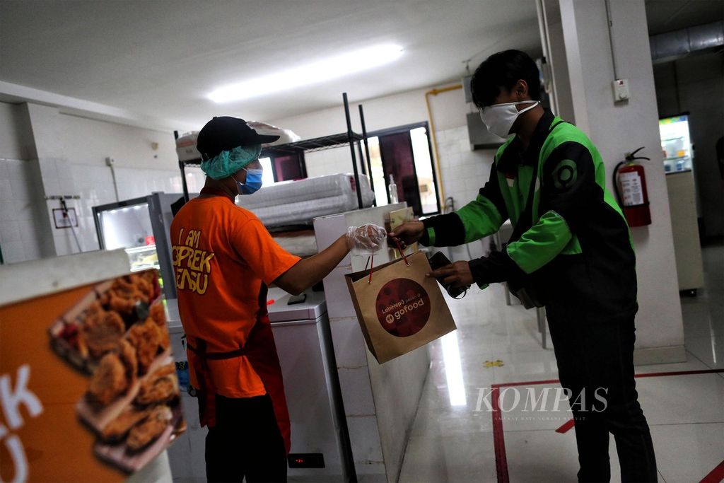 Mitra pengemudi Gojek tiba di Dapur Bersama GoFood Bintaro, Jakarta Selatan, untuk mengambil pesanan makanan, Minggu (20/9/2020). 