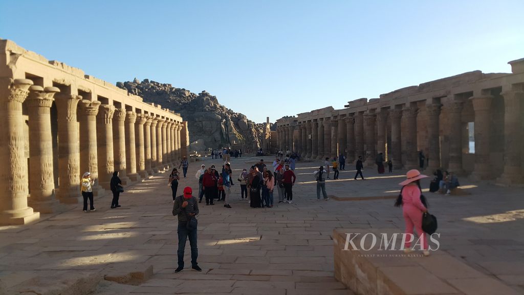 Para turis menikmati pemandangan Candi Philae di kota Aswan, sekitar 900 kilometer selatan kota Kairo, Mesir, Rabu (2/3/2022). Candi Philae dibangun pada era Yunani-Romawi di Mesir pada abad ke-3 Sebelum Masehi.  
