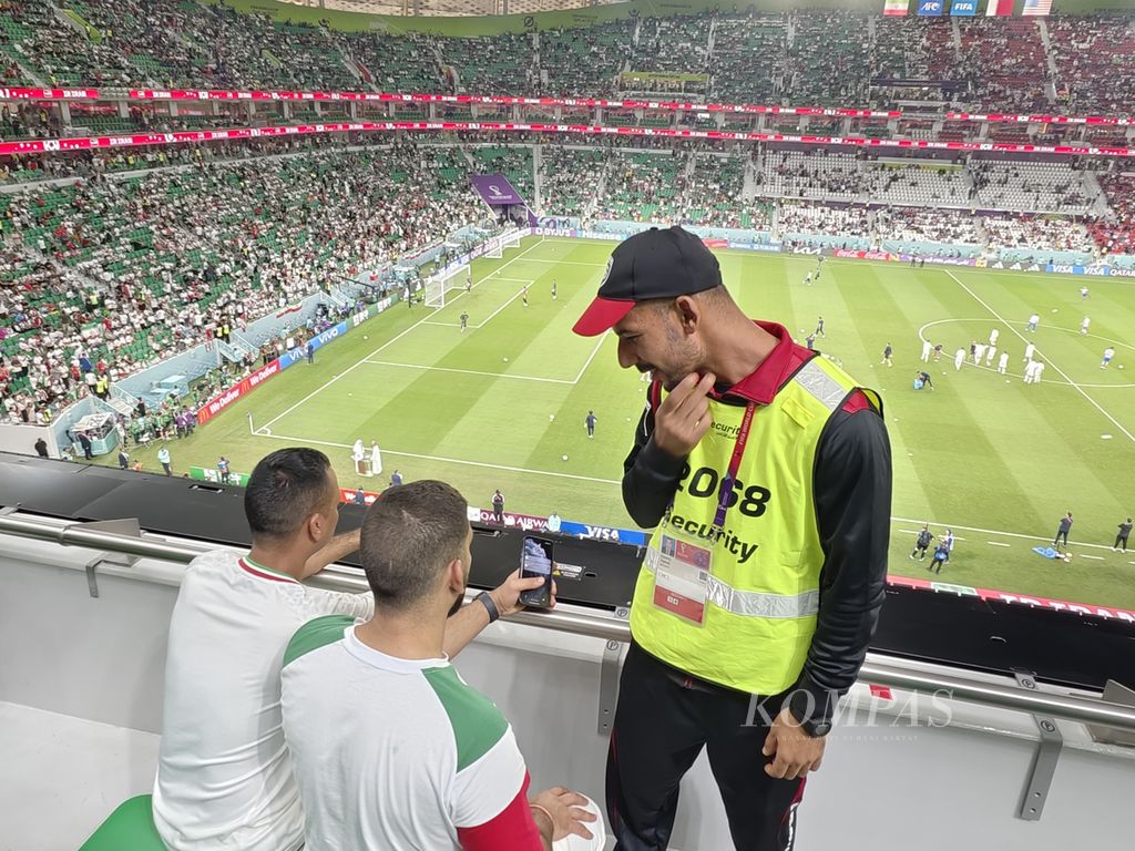Hamdi (kanan), salah satu petugas keamanan di tribune Stadion Al Thumama, Doha, tengah meminta dua pendukung Iran memperlihatkan tiket mereka jelang laga Iran versus Amerika Serikat, Rabu (30/11/2022). Petugas keamanan Piala Dunia 2022 adalah warga sipil dan tidak membawa senjata.