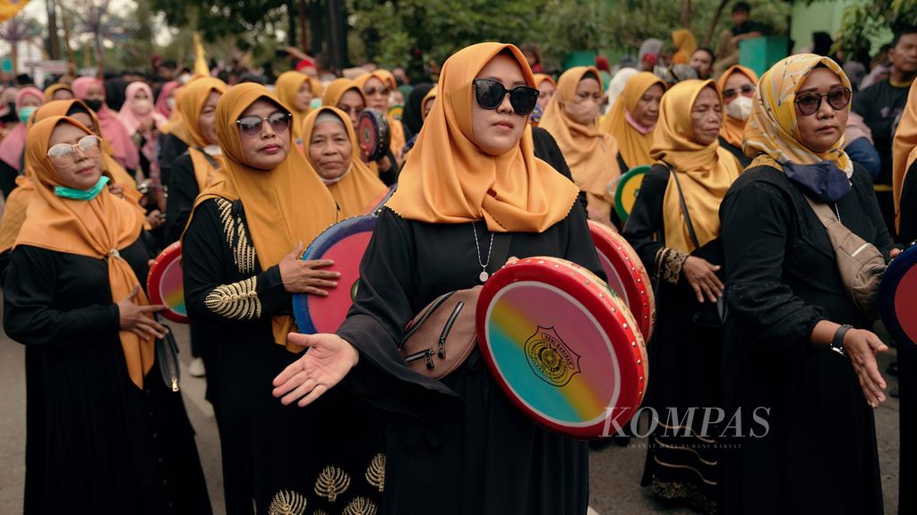 Warga menyanyikan kasidah diiringi rebana dalam arak-arakan Festival Adu Bedug dan Dondang Ke-15 Kecamatan Mustikajaya menuju Stadion Natrom Nursyamsu, Kota Bekasi, Jawa Barat, Minggu (22/5/2022). 