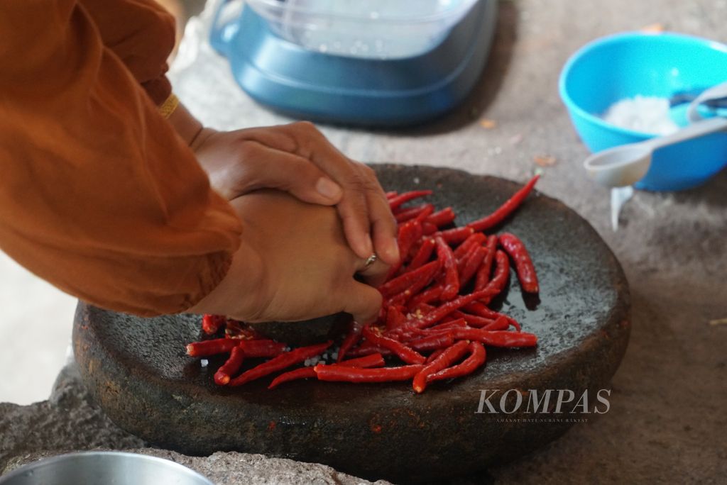 Warga menggiling cabai merah untuk membuat samba lado tulang di Nagari Parambahan, Kecamatan Limo Kaum, Tanah Datar, Sumatera Barat, Jumat (27/5/2022). Samba lado tulang adalah makanan khas masyarakat Tanah Datar.