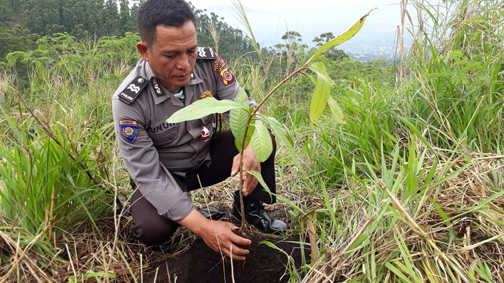 Aiptu Nunuh Sutisna ikut menanam bibit pohon di Legok Terong, Ibun, Kabupaten Bandung, Jawa Barat. Sabtu (26/12/2020). Anggota Polri ini aktif menggerakkan penanaman pohon serta pelestarian lingkungan hidup di sejumlah daerah di Jabar.