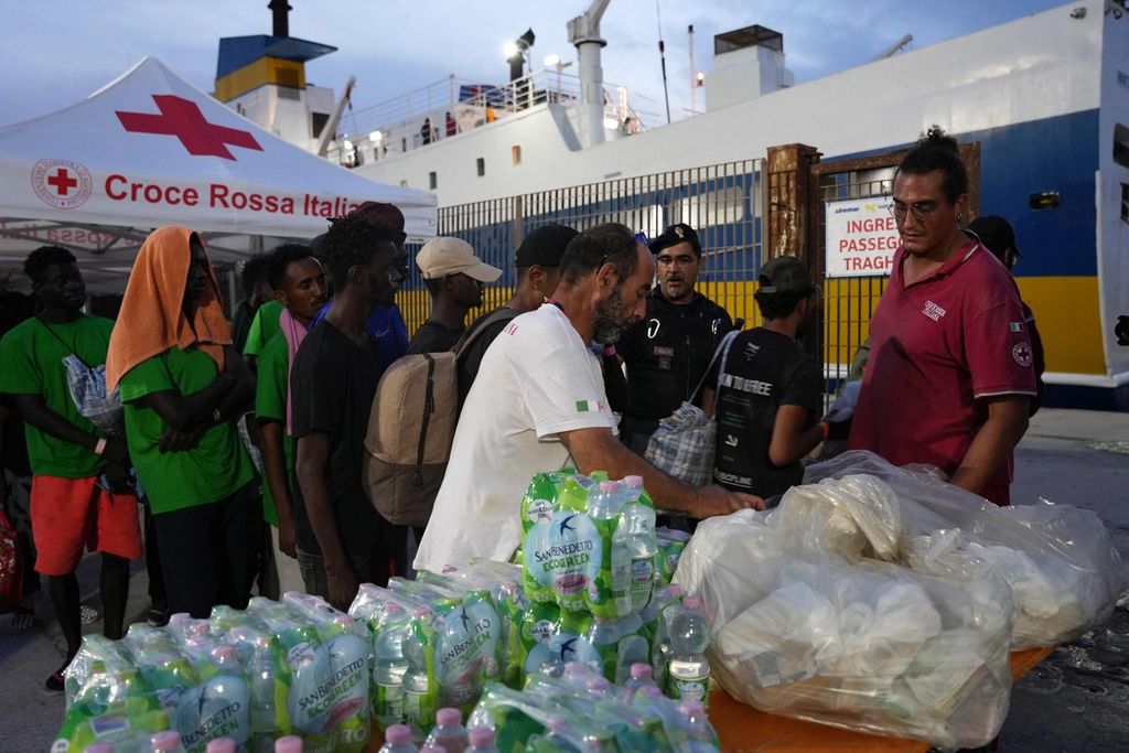 Sukarelawan Palang Merah Italia membagikan makanan dan minuman kepada pengungsi yang baru tiba di Pulau Lampedusa, Italia, pada 16 September 2023. Pemerintah Lampedusa mengaku kewalahan dengan gelombang pengungsi dari Afrika. 