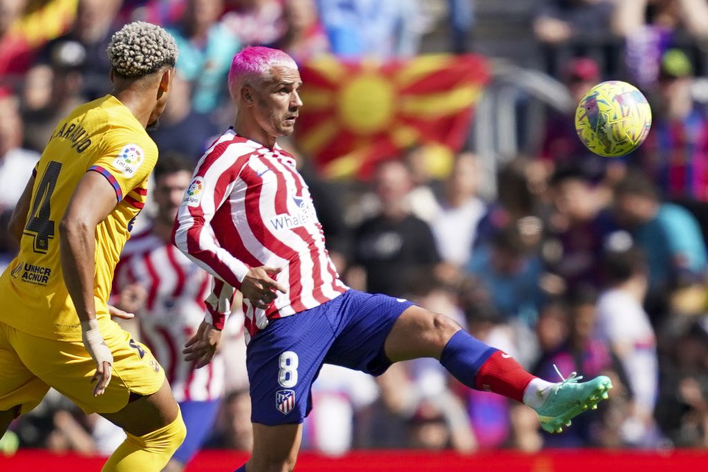 Pemain Atletico Madrid Antoine Griezmann (kanan) berebut bola dengan pemain Barcelona Ronald Araujo pada laga Liga Spanyol di Stadion Camp Nou, Barcelona, Spanyol, Minggu (23/4/2023). Barcelona menang dengan skor 1-0.