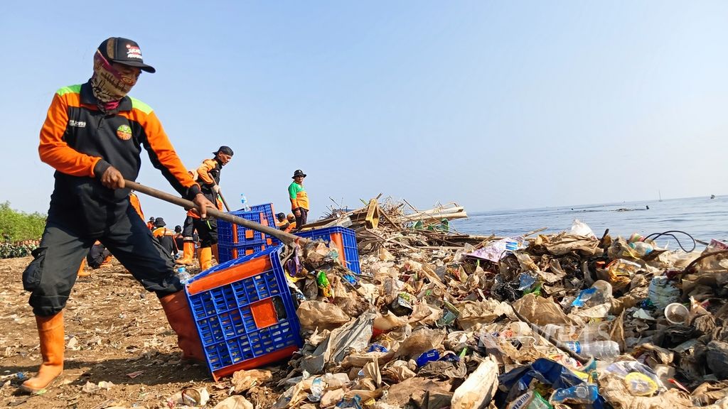 Petugas kebersihan mengais dan memasukkan sampah ke keranjang di pesisir Muara Kali Adem, Penjaringan, Jakarta Utara, Sabtu (7/9/2024).