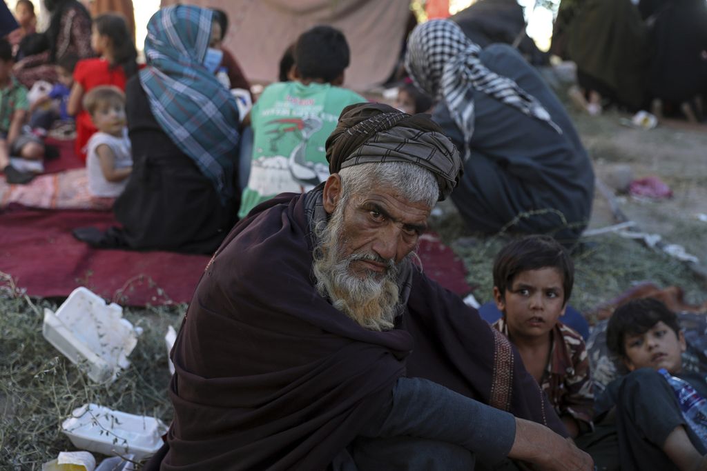 Seorang pengungsi lelaki Afghanistan duduk bersama beberapa orang anak di sebuah lokasi di Kota Kabul, Afghanistan, Agustus tahun 2021. Lembaga penelitian Gallup menempatkan Afghanistan sebagai negara paling tidak bahagia di dunia saat ini.