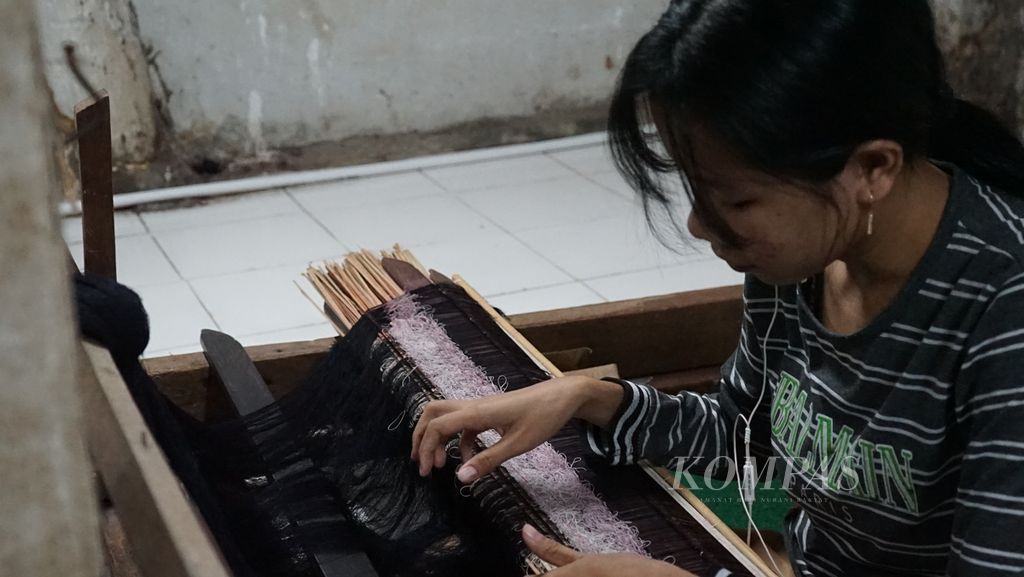 Seorang petenun menenun songket di kawasan Tangga Buntung, Palembang, Jumat (18/2/2022). Kawasan ini menjadi salah satu sentra pembuatan kain songket di Palembang. Tradisi menenun songket di tempat ini diduga sudah berlangsung sejak ratusan tahun lalu.