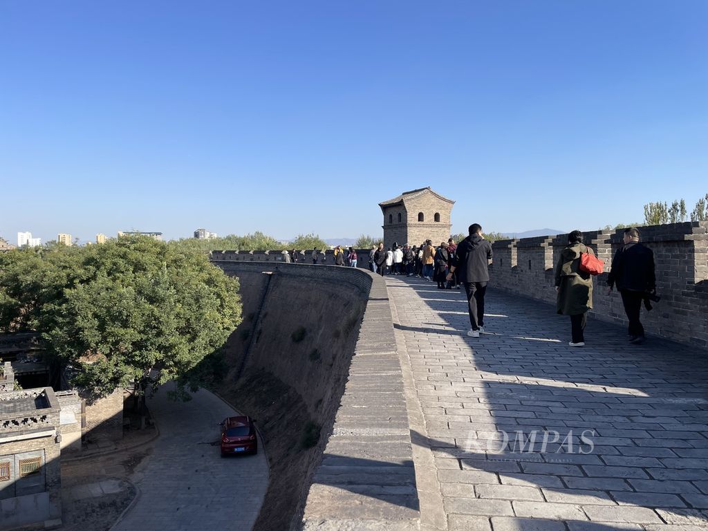 Para pengunjung berjalan mengelilingi tembok benteng sepanjang 6 kilometer di kota kuno Pingyao, Provinsi Shanxi, China, 20 Oktober 2023.