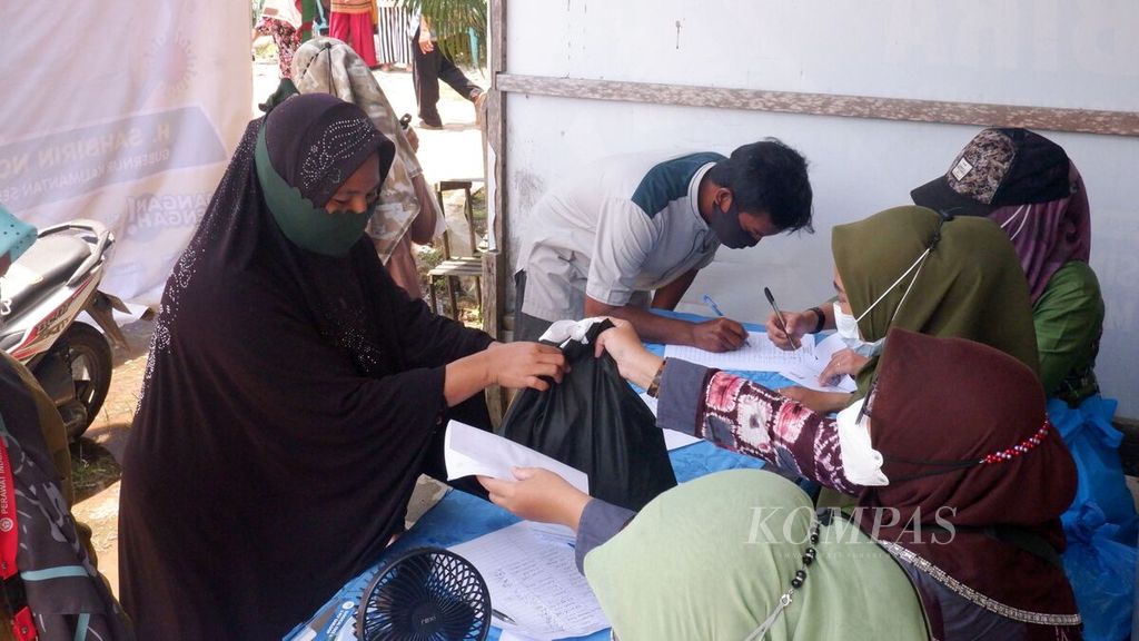Warga menerima paket bahan pokok setelah divaksin dalam kegiatan vaksinasi bergerak pada Ramadhan 1443 H di Puskesmas Berangas, Kecamatan Alalak, Barito Kuala, Kalimantan Selatan, Kamis (7/4/2022). 