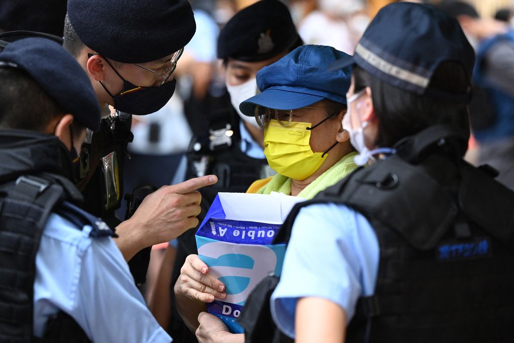 Polisi menanyai seorang perempuan yang memegang kertas kosong di Causeway Bay di Hong Kong, 4 Juni 2022. Aparat melarang penyelenggaraan acara peringatan 33 tahun Tragedi Tiananmen di kawasan tersebut.