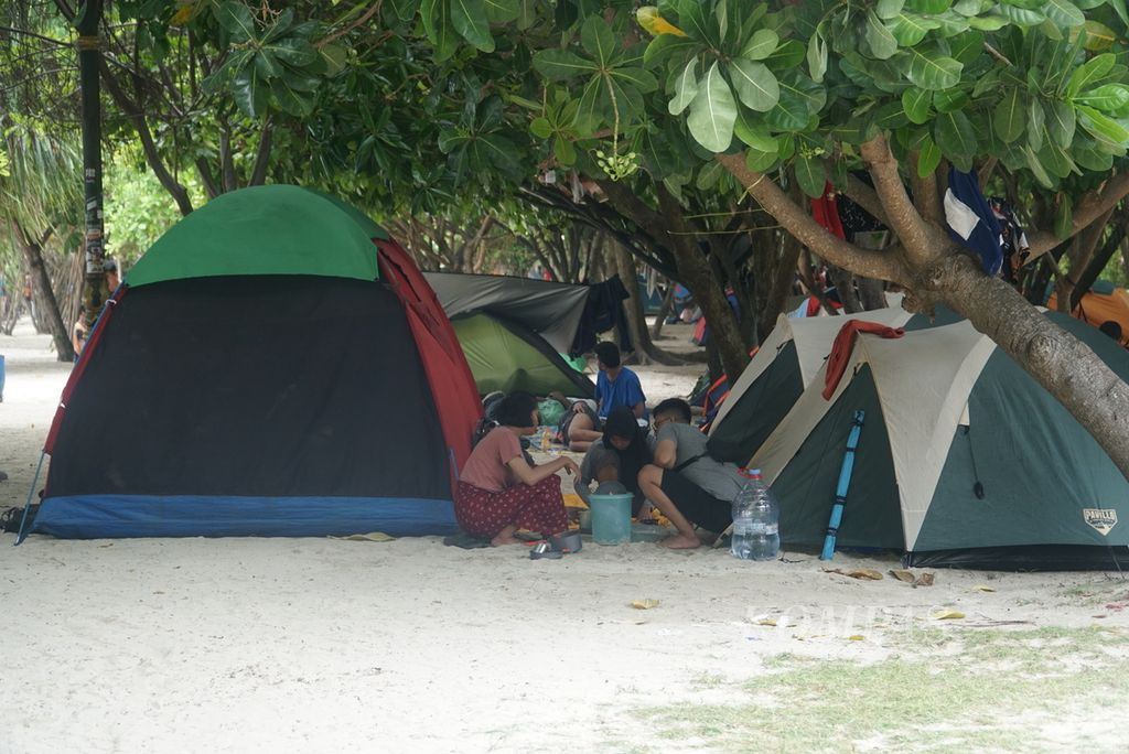 Wisatawan beraktivitas di sekitar perkemahan Pantai Pasir Perawan di Pulau Pari, Kabupaten Administrasi Kepulauan Seribu, Jakarta, Senin (1/1/2024). 