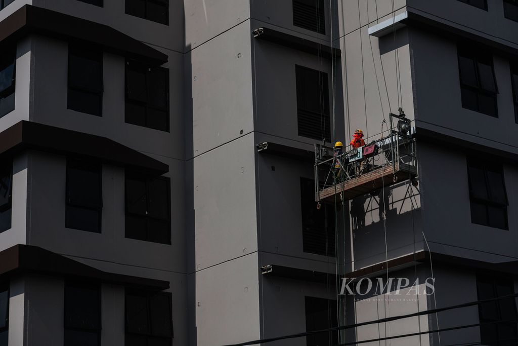 Pekerja bergelantungan menyelesaikan pengerjaan akhir pembangunan sebuah apartemen baru di kawasan Pondok Cabe, Tangerang Selatan, Banten, Senin (9/1/2023). 