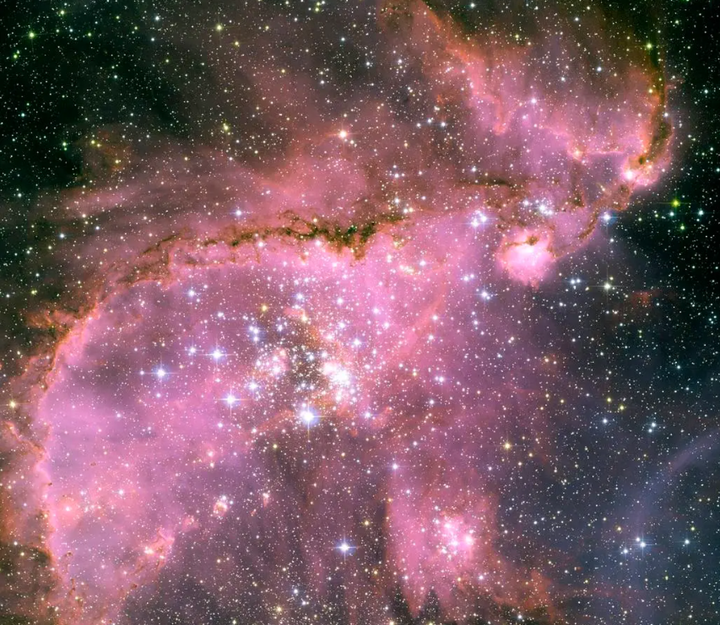 Awan Magellan Kecil, galaksi katai yang merupakan satelit dari Galaksi Bimasakti dan berjarak sekitar 210.000 tahun cahaya dari Bumi. Citra ini diambil oleh Teleskop Luar Angkasa Hubble. Galaksi ini menjadi salah satu tempat yang banyak melahirkan bintang-bintang baru.