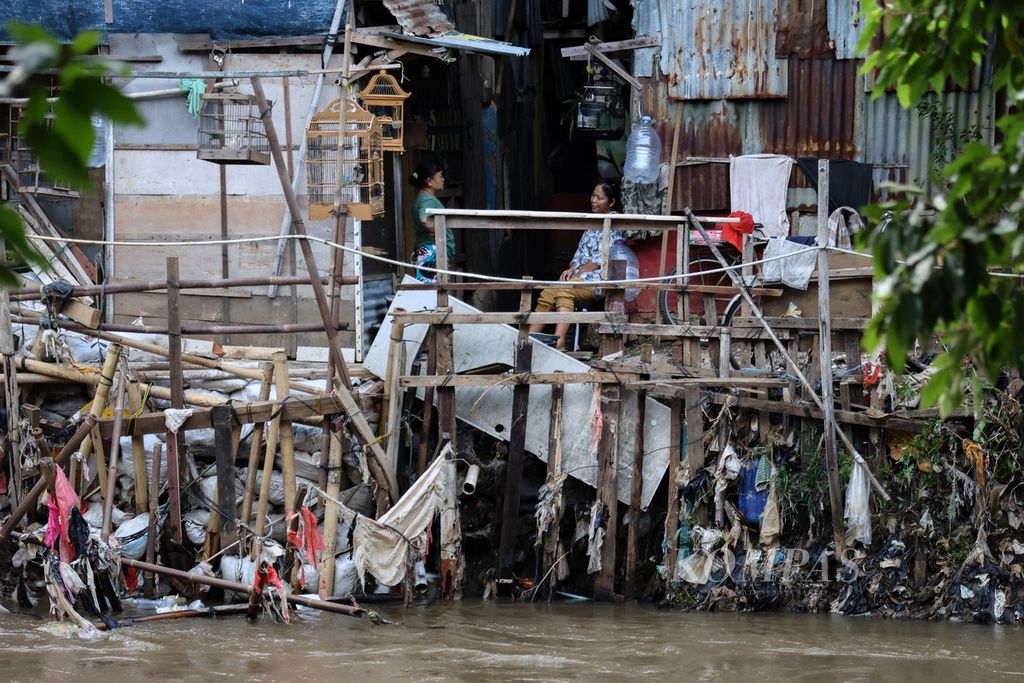 Residents chat beside the Ciliwung River in the Jatinegara area, East Jakarta, Saturday (2/12/2023).