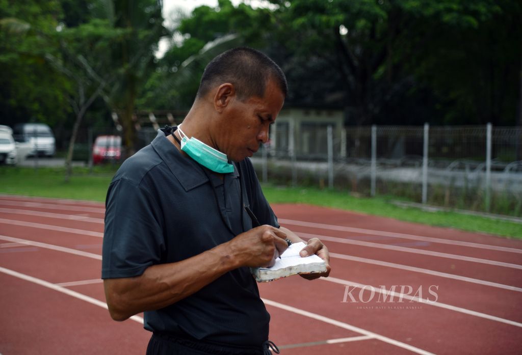 Pelatih pelari putri spesialis 400 meter Sumatera Selatan Sri Mayasari, Bastoni, mencatat perkembangan performa Sri dalam latihan rutin PASI Sumsel di Kompleks Olahraga Jakabaring, Palembang, Sumsel, Kamis (23/11/2023). 