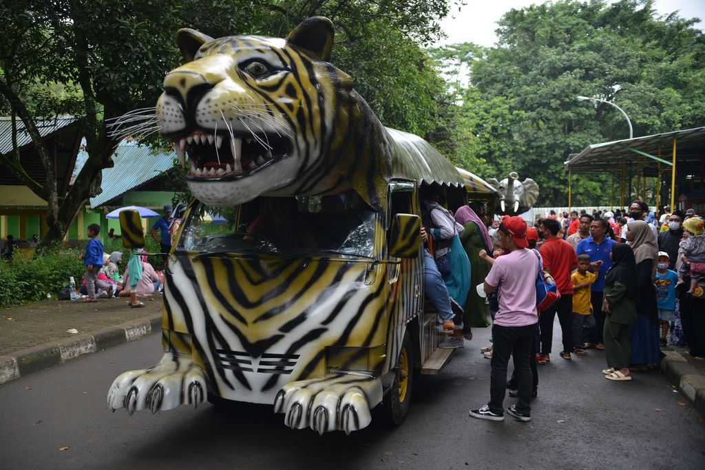 Warga mengantre untuk masuk ke dalam kereta keliling di Kebun Binatang Ragunan, Jakarta Selatan, Minggu (25/12/2022). 