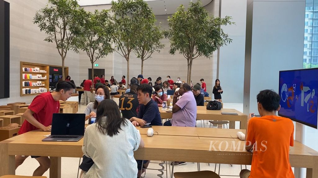 Petugas pelayanan pelanggan di area Genius Bar (baju merah) melayani pengunjung yang memeriksa kerusakan perangkat Apple mereka di Apple Store Orchard Singapura, Sabtu (20/1/2024).
