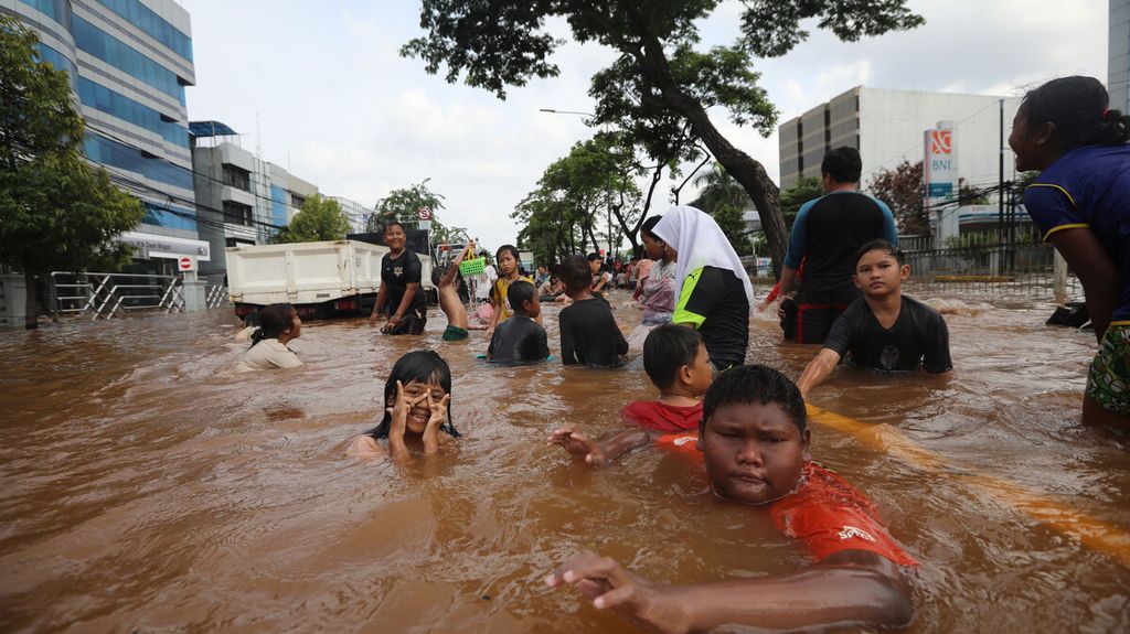 Anak-anak bermain air di genangan banjir Jalan Daan Mogot, Jakarta Barat, Kamis (2/1/2020). Bagi anak-anak, banjir menjadi kesempatan langka untuk bermain air meskipun kotor dan berisiko menularkan penyakit.
