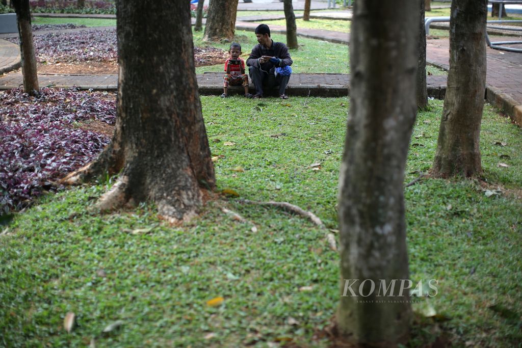 Seorang ayah bermain telepon genggam bersama anaknya di Taman Tangkuban Perahu, Kelurahan Guntur, Kecamatan Setiabudi, Jakarta Selatan, Rabu (13/9/2023). 