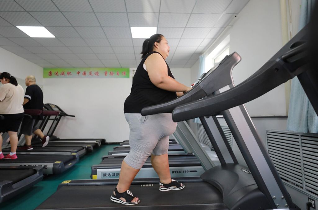 Dalam foto yang diambil pada 17 Juli 2018 ini terlihat seorang perempuan obesitas sedang melakukan <i>treadmill</i> di klinik pengurangan berat badan di Changchun, Provinsi Jilin, China.