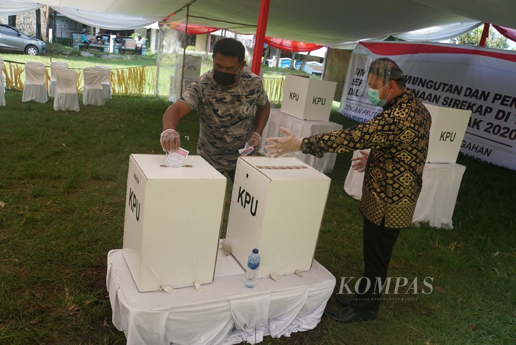 Seorang pemilih memasukkan surat suara setelah mencoblos di bilik suara dalam simulasi Pilkada 2020, Sabtu (21/11/2020), di Lapangan Bantik, Malalayang I, Manado, Sulawesi Utara. Simulasi itu diikuti dua KPPS dan 200 orang warga setempat yang masuk daftar pemilih tetap.