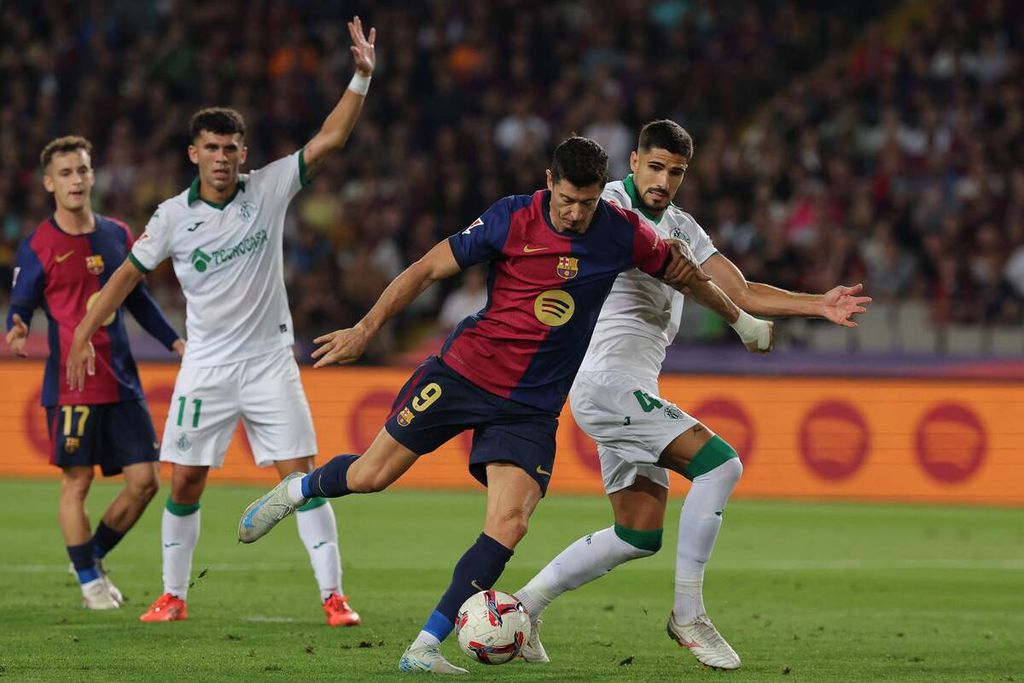 Striker Barcelona, Robert Lewandowski (kedua kanan), berebut bola dengan bek Getafe, Gaston Alvarez, pada laga La Liga di Barcelona, Kamis (26/9/2024) dini hari WIB. Barca menang 1-0 berkat gol Lewandowski.