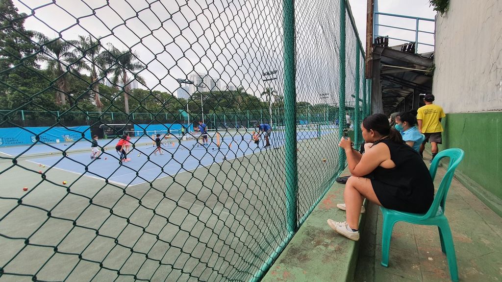 Karyawan swasta, Putri Arifa Malik menunggu anaknya latihan tenis di Lapangan Tenis Gelanggang Olahraga Soemantri Brodjonegoro, Jakarta, Senin (14/11/2022). 