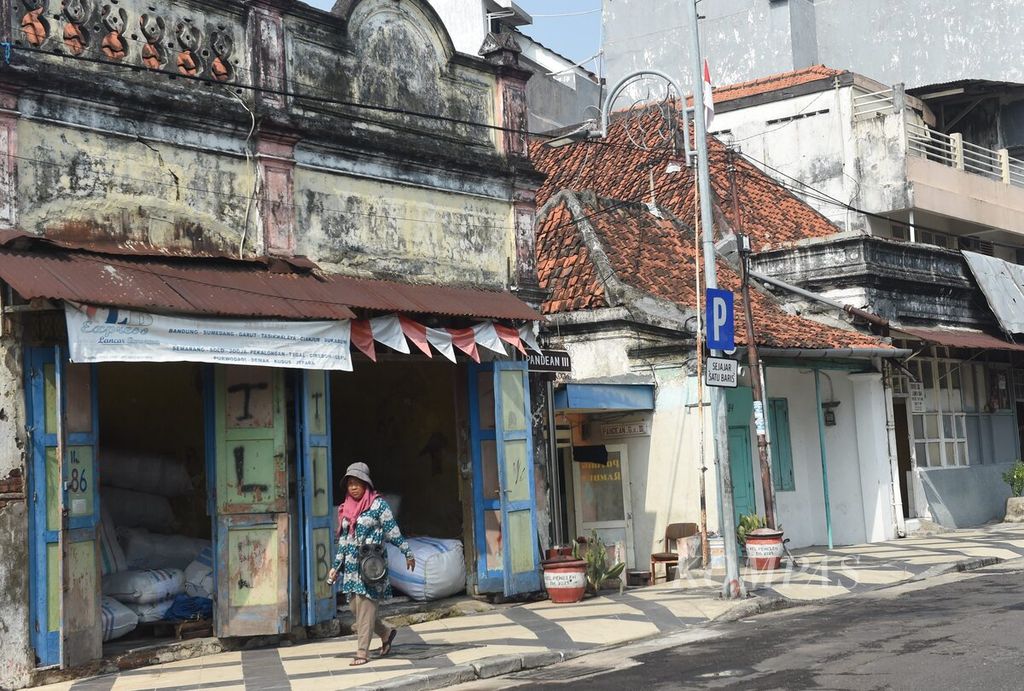 Warga melewati bangunan tua di Kampung Pandean, Surabaya, Jawa Timur, Kamis (6/7/2023). Sejumlah kampung di pinggir Sungai Kalimas masih menampakkan wajah Surabaya pada masa lalu. 