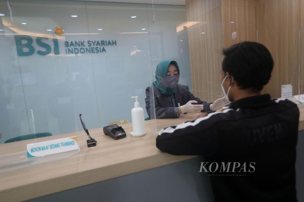 Teller Bank Syariah Indonesia melayani nasabah di Kantor Cabang Hasanudin, Blok M, Jakarta, Senin (1/2/2021). Bank yang merupakan hasil merger dari PT Bank BRI Syariah Tbk, PT Bank BNI Syariah, dan PT Bank Syariah Mandiri tersebut, resmi beroperasi pada Senin (1/2/2021). Bank beraset Rp 240 triliun ini diharapkan dapat memberikan efek domino bagi ekonomi syariah dan rantai pasok industri halal dalam negeri. BSI saat ini berada di posisi ke-7 dalam daftar sepuluh besar bank terbesar di Indonesia dari sisi aset. 