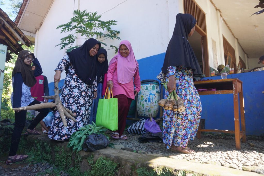 Wali murid membawa aneka hasil bumi untuk mendaftarkan anaknya sekolah di MTs Pakis di Desa Gununglurah, Cilongok, Banyumas, Jawa Tengah, Rabu (12/7/2023).