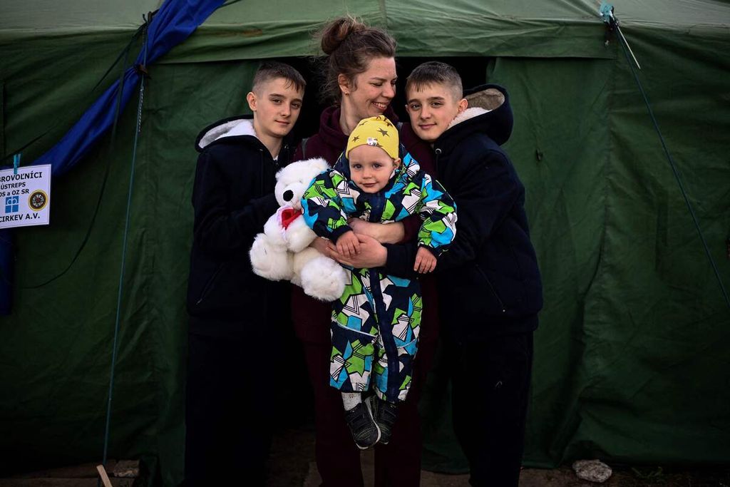 Pengungsi Ukrainan, Tetyana Dzymik (tengah), berpose dengan anak-anaknya di depan sebuah tenda di penampungan pengungsi di perbatasan Ukraina-Slovakia pada Jumat (8/4/2022). 