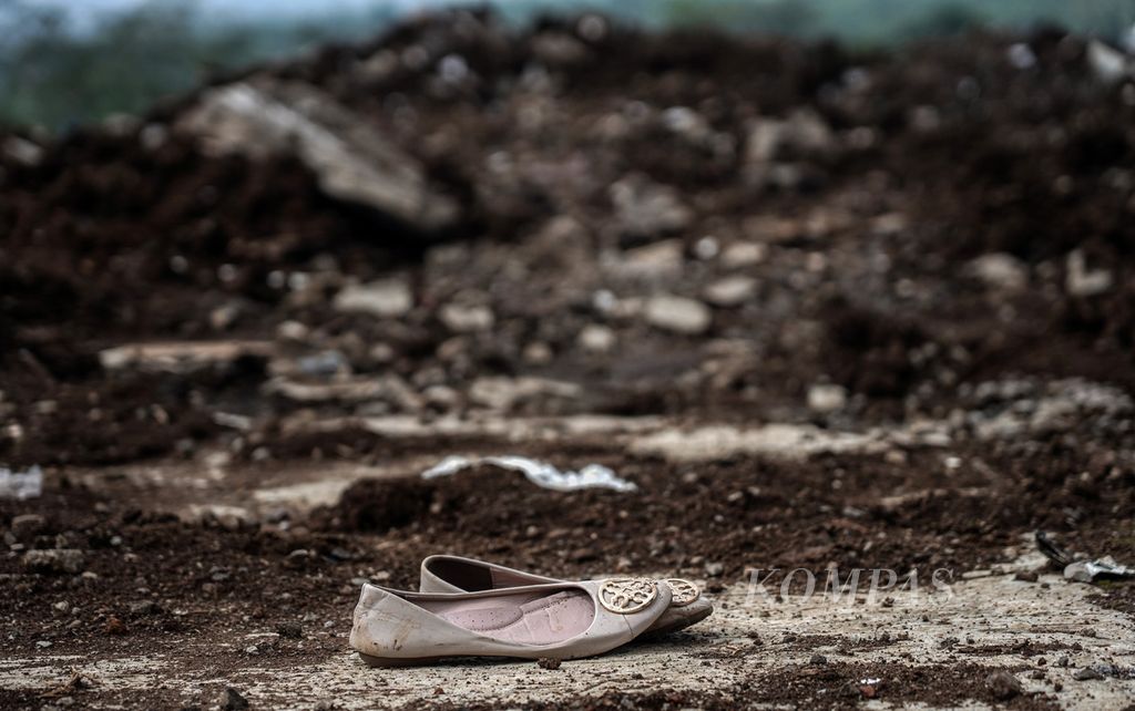 Sepasang sepatu wanita yang ditemukan di antara timbunan tanah longsor akibat gempa di sekitar Warung Sate Shinta, Jalan Raya Cipanas-Cianjur, Cugenang, Kabupaten Cianjur, Jawa Barat, Senin (28/11/2022). 
