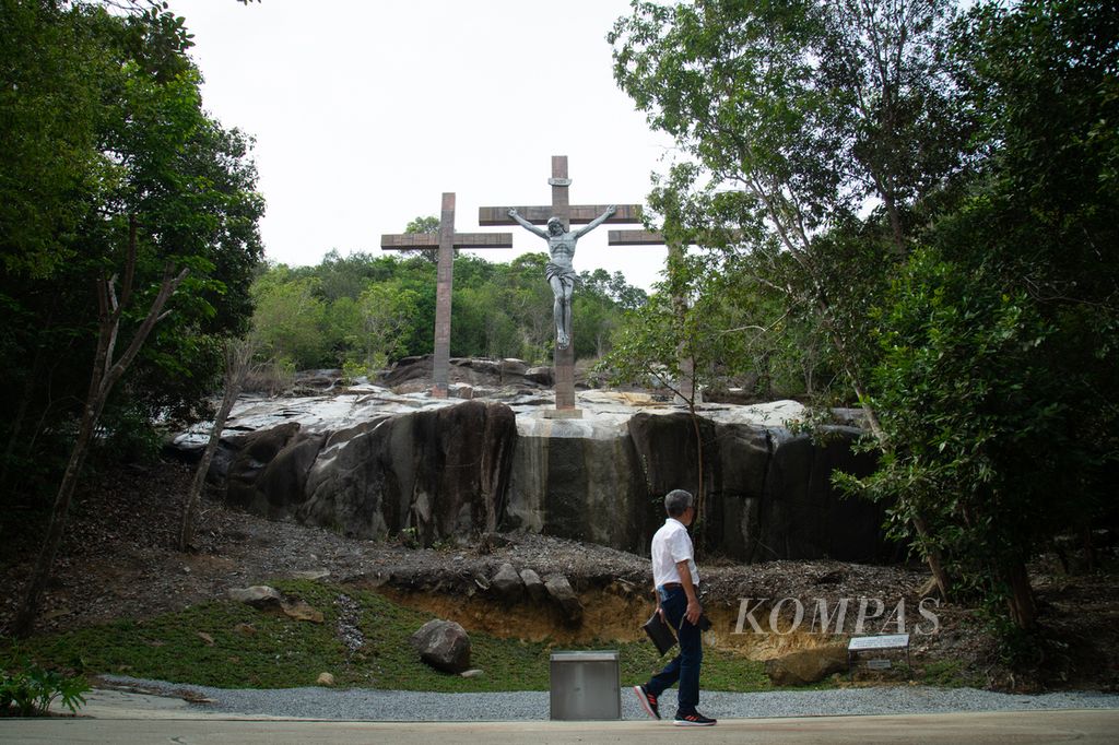 Peziarah melintas di depan salib yang didirikan di atas batu granit alami di Taman Bintang Samudra di Kabupaten Bangka, Kepulauan Bangka Belitung, Rabu (24/1/2024).