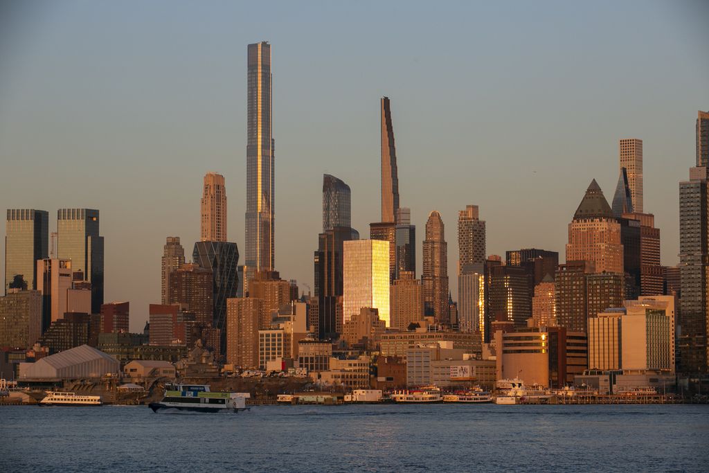 Arsip. Cahaya matahari terbenam memantulkan bangunan di wilayah Manhattan di New York, AS, terlihat dari Dermaga Weehawken di Weehawken, 22 Maret 2023. 