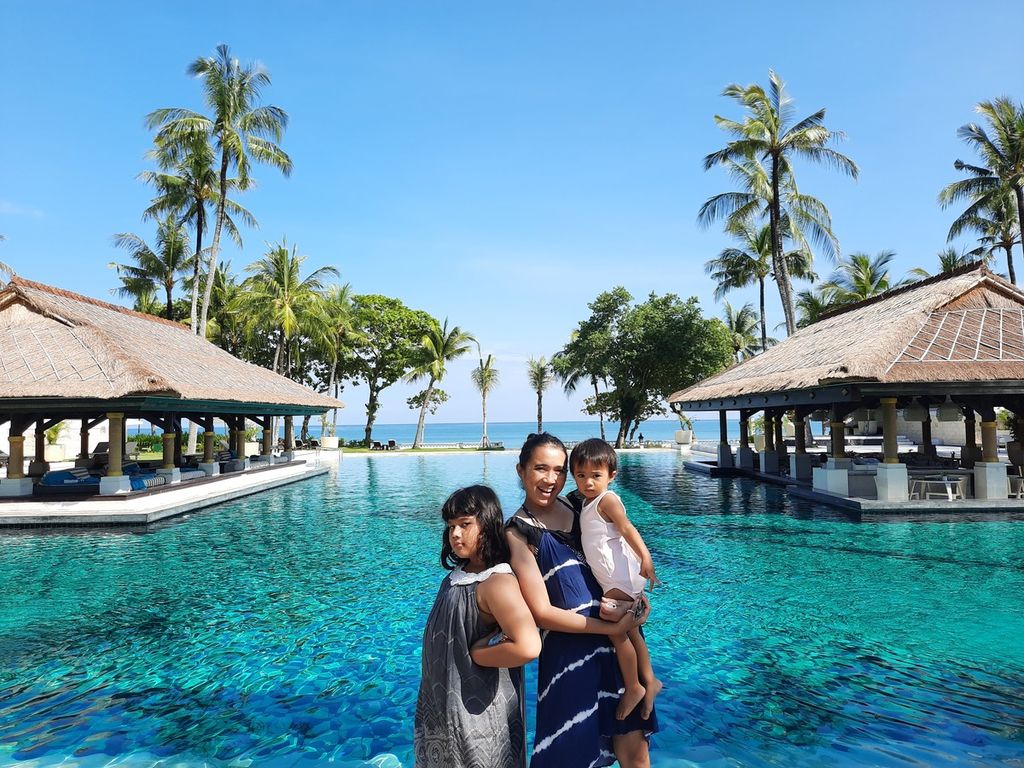Wisatawan lokal berfoto di depan kolam renang Hotel Intercontinental, Bali, yang berada di tepi pantai, Sabtu (23/4/2022).