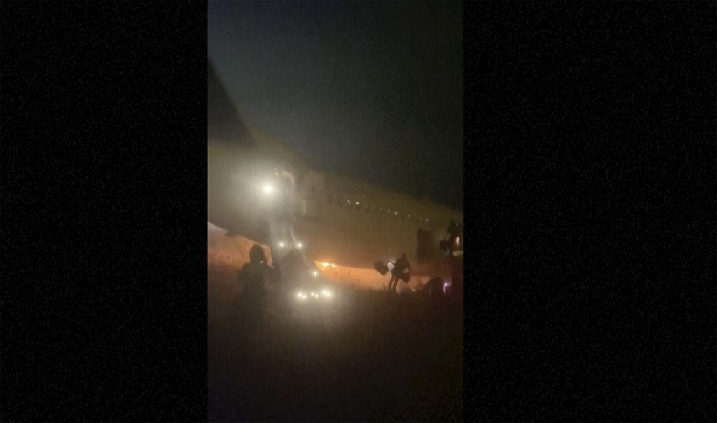 Foto yang dicuplik dari rekaman video menunjukkan penumpang keluar menggunakan perosotan darurat dari pesawat Boeing 737 yang dioperasikan Air Senegal yang terbakar dan keluar dari landas pacu di Bandara Dakar, Rabu (8/5/2024). 