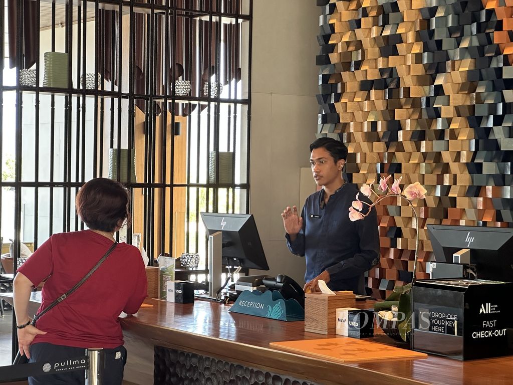 Johan Perdana, warga Lombok Tengah yang menjadi resepsionis di Pullman Lombok Merujani Mandalika Beach Resort, memberikan informasi kepada salah seorang tamu hotel tersebut pada Sabtu (5/8/2023). Saat ini, sebanyak 91 persen dari sekitar 200 karyawan di Pullman Lombok merupakan warga lokal.